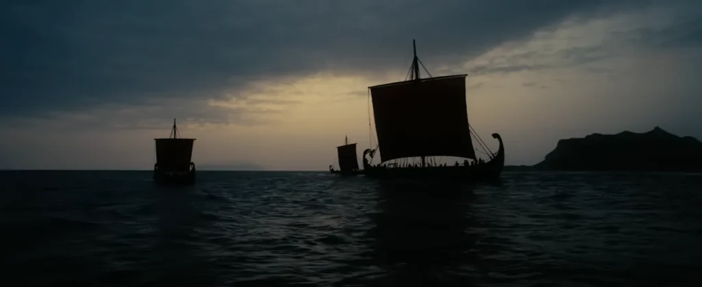 سفن شراعية قديمة تعبر البحر عند الغروب في لقطة من تريلر فيلم The Odyssey